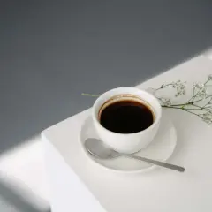 En kopp svart kaffe med en sked och en liten blomsterkvist. Perfekt för en stunds avkoppling med kaffe efter maten.