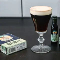 En elegant kaffedrink med krämig topping, bredvid en ask och två små flaskor Branca Menta.
