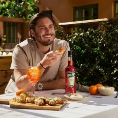 Man njuter av en solig stund med en läcker alkoholfri kaffedrink, tilltugg och en flaska Aperol.