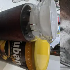 En stor glasburk med kondens fylld med mörkt, gammalt kaffe står bredvid en gul burk med "ubán Gold" kaffe.