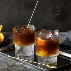 Två glas med kaffe tonic, is och apelsinskivor på ett fat.