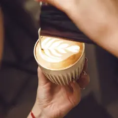 En barista skapar vackert latte art i en kopp kaffe latte.