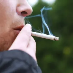 En person röker en cigarett med mentolsmak utomhus i Sverige.