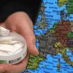 En hand håller en prilla snus framför en karta över Europa, med fokus på Danmark och Sverige. Copenhagen snus Sverige.