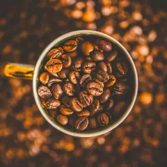 En kopp fylld med kaffebönor, redo att bli en härlig dryck. Kanske en liten barnkopp för en lekfull fika?