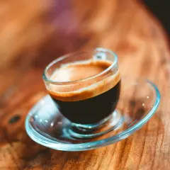 En kopp med en gyllene crema, en perfekt lungo kaffe, står på ett träbord.