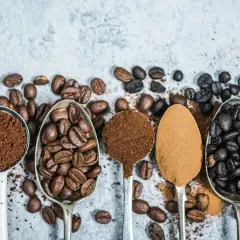 Fem skedar visar olika stadier av kaffe produktion: från hela bönor till fint malet pulver.