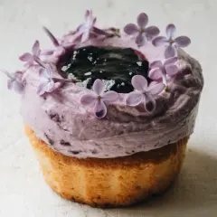 En lila cupcake med blåbärsfrosting, mörka bär och syrenblommor. Ett recept inspirerat av Starbucks.