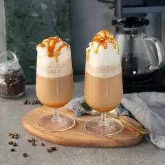Två glas med krämig frappe caramel, toppade med vispgrädde och karamellsås. Perfekt för en fika.