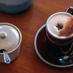 En kopp värmande chai latte med stjärnanis och kanel, bredvid en sockerskål med sked.