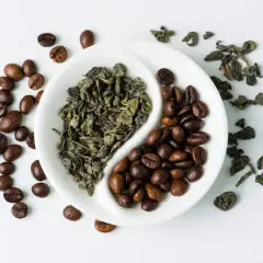 En vit skål delar torkade teblad och kaffebönor. Jämförelse av koffein i te vs kaffe.