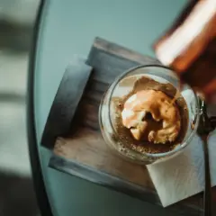 Varm espresso hälls över vaniljglass i en klassisk cafe affogato. En sked ligger bredvid.