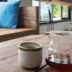 En kaffebryggare i glas med kaffe och en kopp på ett träbord. Perfekt kaffebryggare temperatur för en njutbar stund.