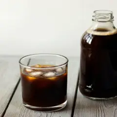 Ett glas islat kaffe bredvid en flaska med kallbryggt kaffe. Perfekt för ett enkelt cold brew recept.