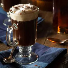 En värmande irish coffee med rom, toppad med fluffigt grädde och en nypa kanel. Perfekt för en mysig kväll.