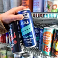 Hand tar en energidryck ur ett kylskåp. Frågan om att dricka energidryck gravid är relevant.