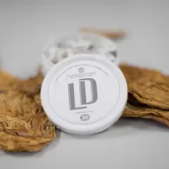 En dosa LD snus ligger på torkade tobaksblad, en del av snus tillverkning.