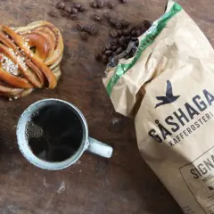 En kanelbulle, chokladmuffin och en kopp kaffe. Perfekt för en **fika paus** med kaffebönor och en påse Gåshaga Kafferosteri.