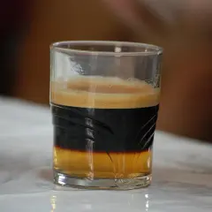 En spansk kaffedrink med lager av kaffe och skum i ett glas.