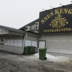SnusKungen, the king of snus, med sitt gyllene emblem och text på fasaden. En restaurang finns till vänster.
