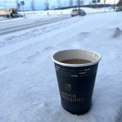 En kopp kaffe från Arvid Nordquist står i snön. Undrar vad kostar en kopp kaffe hemma? En varm dryck i vinterkylan.