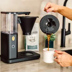 En kaffebryggare som visar hur fungerar en kaffebryggare, med nybryggt kaffe som hälls upp i en mugg.