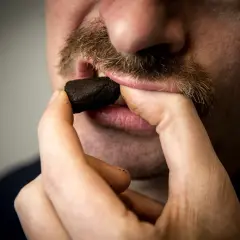 Man med mustasch placerar en prilla snus, kanske det dyraste snuset, i munnen.