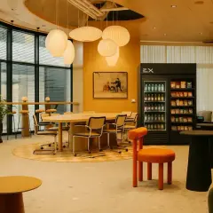En modern arbetsplats med bekväma sittplatser, ett stort bord och en kyl med snacks, perfekt för en fika på jobbet.
