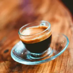 En liten kopp espresso ristretto med krämig crema på ett träbord.