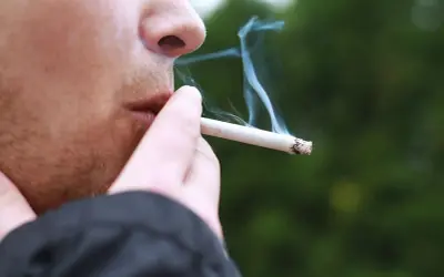 En person röker en cigarett med mentolsmak utomhus i Sverige.