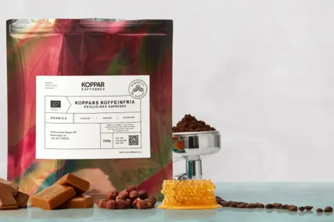 En påse med "Koppars Kaffeinfria Ekologiska Espresso" bredvid choklad, hasselnötter och honungskaka. Perfekt för en liten espresso.