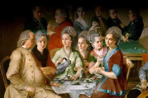 En grupp människor samlas runt ett bord för att dricka kaffe, en scen som speglar kaffets historia och dess sociala betydelse.