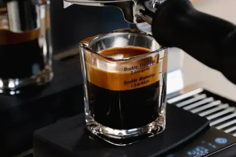 A double ristretto and double espresso in a glass shot with measurement markings.