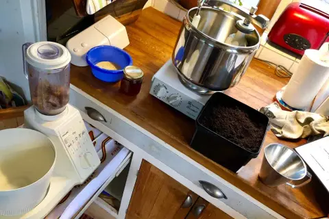 Förbereder för att mala tobak till snus. Köksbänk med mixer, skål med tobak, burk med honung och en köksmaskin.