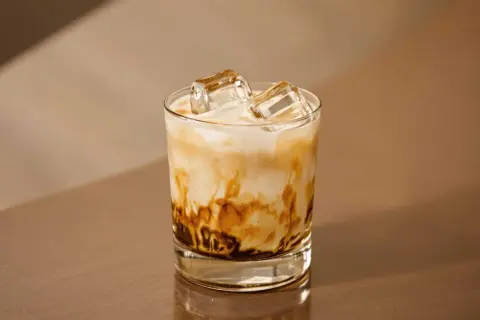 En glas med freddo cappuccino, is och mjölk som virvlar i en vacker marmorering. Perfekt för en varm sommardag.
