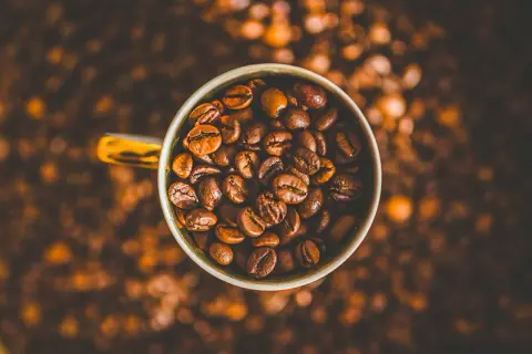 En kopp fylld med kaffebönor, redo att bli en härlig dryck. Kanske en liten barnkopp för en lekfull fika?