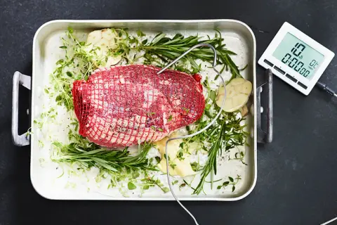 Råstek med örter och vitlök i ugnsform, redo att koka te. En digital termometer visar 10°C.