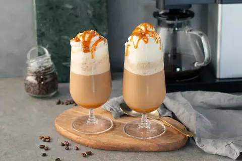 Två glas med krämig frappe caramel, toppade med vispgrädde och karamellsås. Perfekt för en fika.