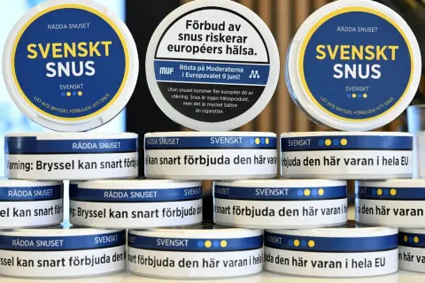 Stackar av vita snusdosor med texten "SVENSKT SNUS" och uppmaningar att rädda snuset.