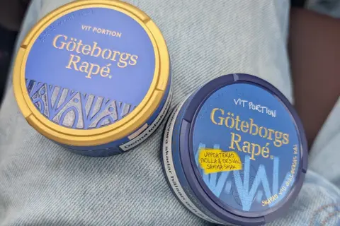 Två dosor Göteborgs Rapé, en med guldig kant, ligger på jeans. Perfekt för dig som vill ha snus som inte rinner.