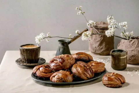 En kopp kaffe och kanelbullar, en klassisk kombination för fika i Sverige. Våren är här med blommande körsbärsgrenar.