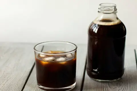 Ett glas islat kaffe bredvid en flaska med kallbryggt kaffe. Perfekt för ett enkelt cold brew recept.