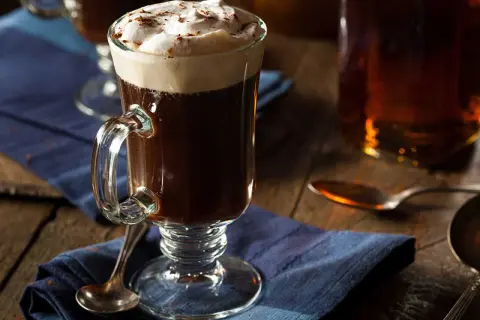 En värmande irish coffee med rom, toppad med fluffigt grädde och en nypa kanel. Perfekt för en mysig kväll.