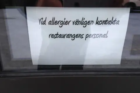 En lapp på ett fönster uppmanar: "Vid allergier vänligen kontakta restaurangens personal." Perfekt för den som är allergisk mot kaffe och vill vara säker.
