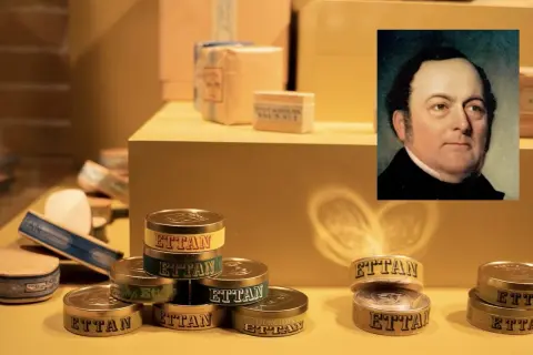 Porträtt av en man bredvid staplar av snusdosor med texten "Ettan". En historisk fråga är vem uppfann snus.