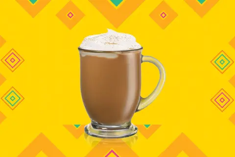 En krämig kaffedrink med kahlua, toppad med vispgrädde och kanel, mot en färgglad bakgrund.