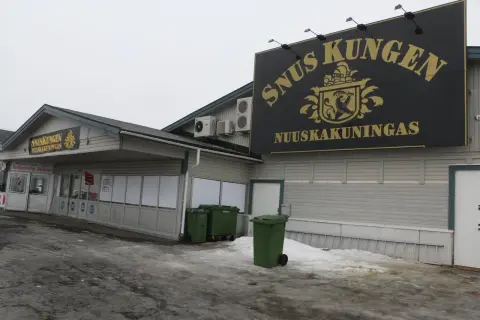 SnusKungen, the king of snus, med sitt gyllene emblem och text på fasaden. En restaurang finns till vänster.
