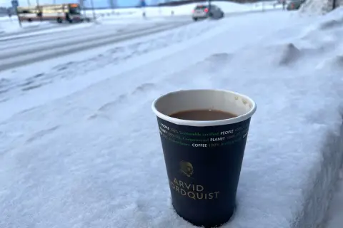 En kopp kaffe från Arvid Nordquist står i snön. Undrar vad kostar en kopp kaffe hemma? En varm dryck i vinterkylan.