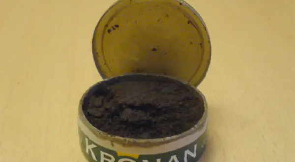 En öppen snusdosa med snus. Kronan-loggan syns tydligt. En klassisk snusdosa storlek.