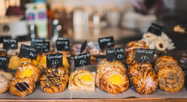 Frestelser på ett café. Vackra bullar och wienerbröd med prislappar, redo att avnjutas med en kopp kaffe.